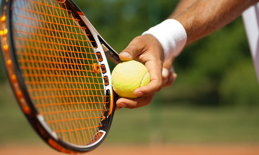 Person holding tennis racquet and ball